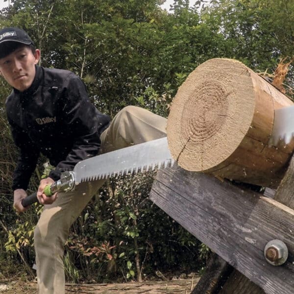 Man sawing log with Silky saw.