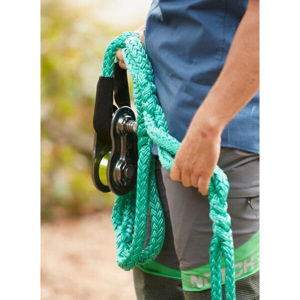 Person holding green rope and pulley.